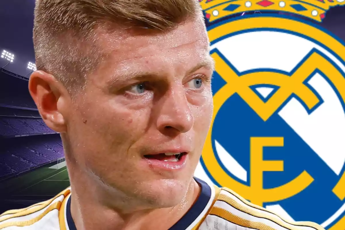 Futbolista amb uniforme blanc i detalls daurats en primer pla amb l’escut del Reial Madrid i un estadi de fons