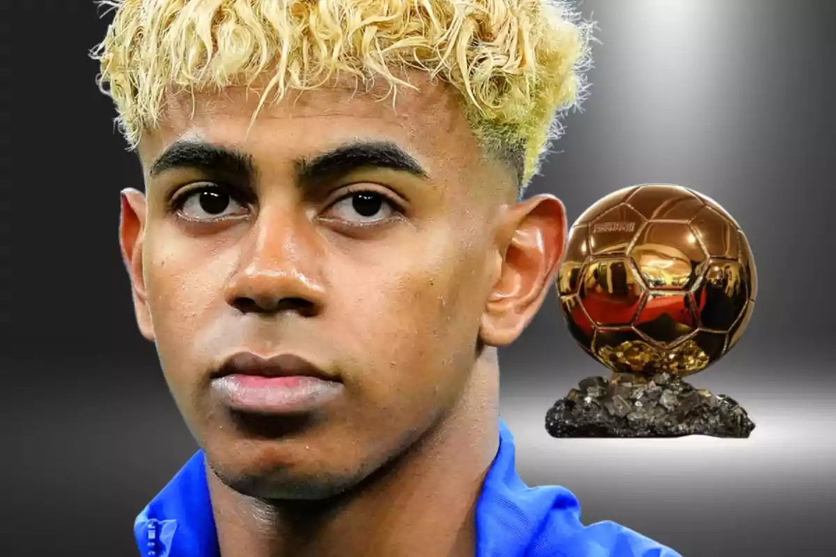 Jove amb cabell ros arrissat i jaqueta blava apareix en primer pla amb un trofeu daurat de pilota de futbol al fons sobre un fons gris difuminat