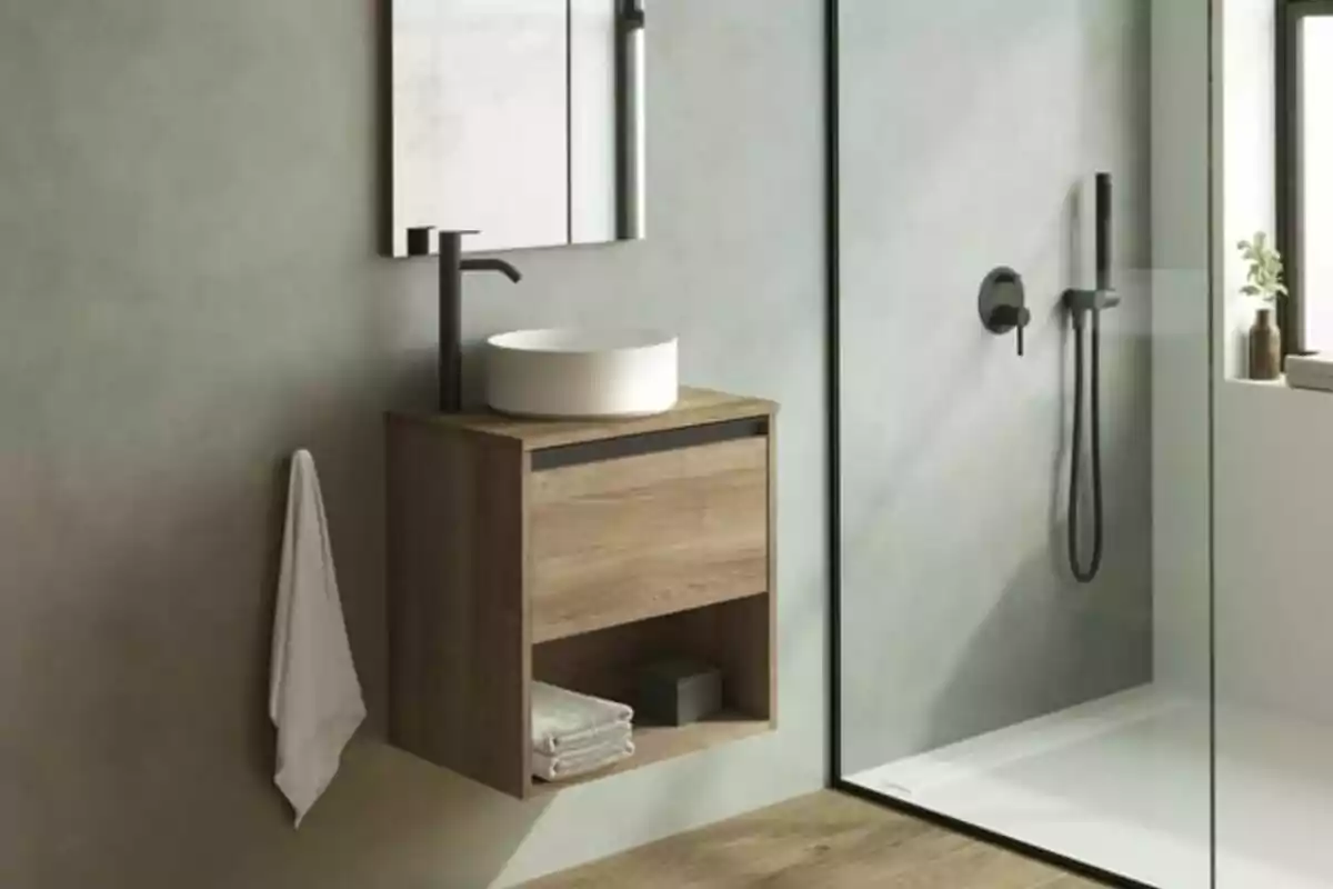 Baño moderno con lavabo de sobreponer, mueble de madera, toalla colgada y ducha con mampara de vidrio Baño moderno con lavabo de sobreponer, mueble de madera, toalla colgada y ducha con mampara de vidrio