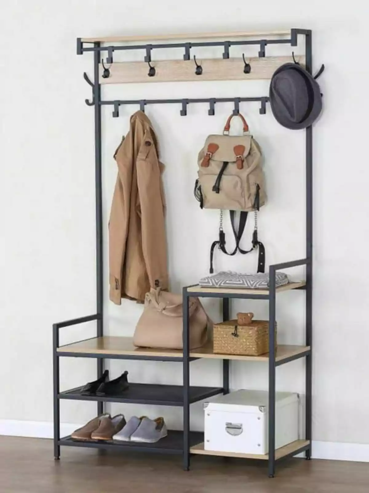 Moble organitzador d’entrada amb ganxos per penjar roba i accessoris, prestatges amb sabates, una caixa blanca, una cistella i diversos objectes personals Moble organitzador d’entrada amb ganxos per penjar roba i accessoris, prestatges amb sabates, una caixa blanca, una cistella i diversos objectes personals