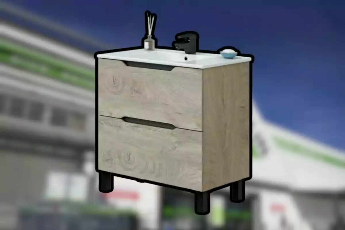 Moble de bany de fusta clara amb dos calaixos, lavabo blanc, aixeta negra i accessoris sobre l’encimera, fons desenfocat