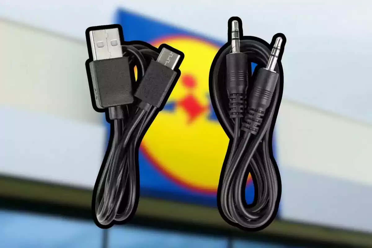 Dos cables negros uno USB y otro auxiliar frente a un letrero borroso de una tienda