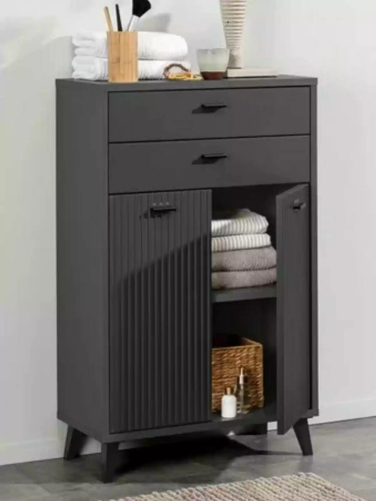 Black furniture with two upper drawers and two lower doors, decorated with towels, a wicker basket, and bathroom items. Black furniture with two upper drawers and two lower doors, decorated with towels, a wicker basket, and bathroom items.