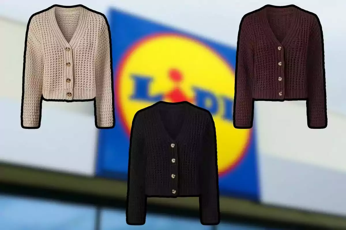 Tres jerseis de punt en colors beix, negre i marró amb botons grans al davant, sobre un fons desenfocat d’un rètol de supermercat.