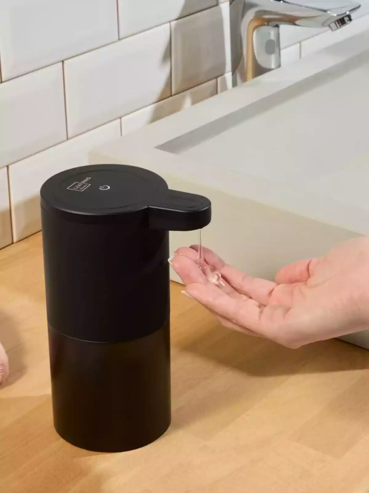 Person using an automatic liquid soap dispenser in a modern bathroom Person using an automatic liquid soap dispenser in a modern bathroom