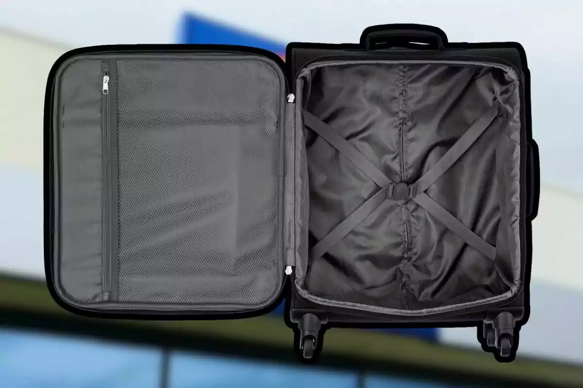 Maleta de viaje negra abierta mostrando su interior vacío con compartimentos y correas elásticas para sujetar la ropa Maleta de viaje negra abierta mostrando su interior vacío con compartimentos y correas elásticas para sujetar la ropa