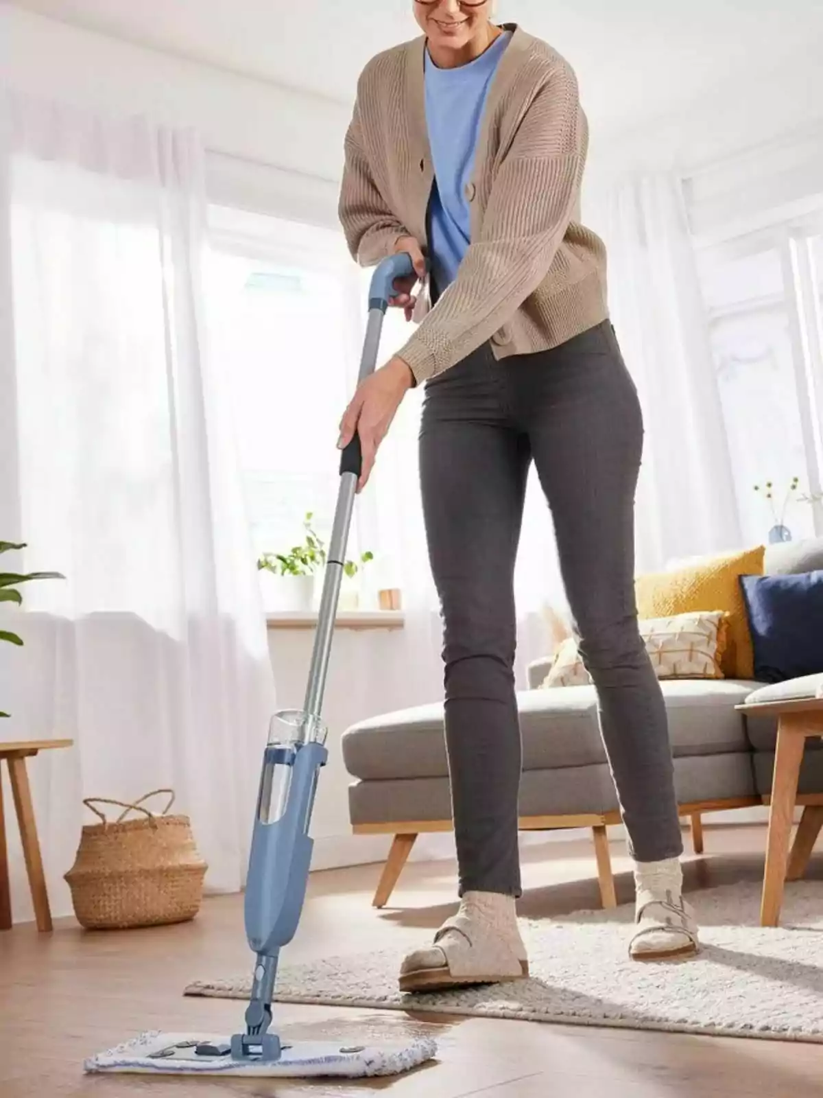 Mujer limpiando el suelo de una sala luminosa con un trapeador de spray