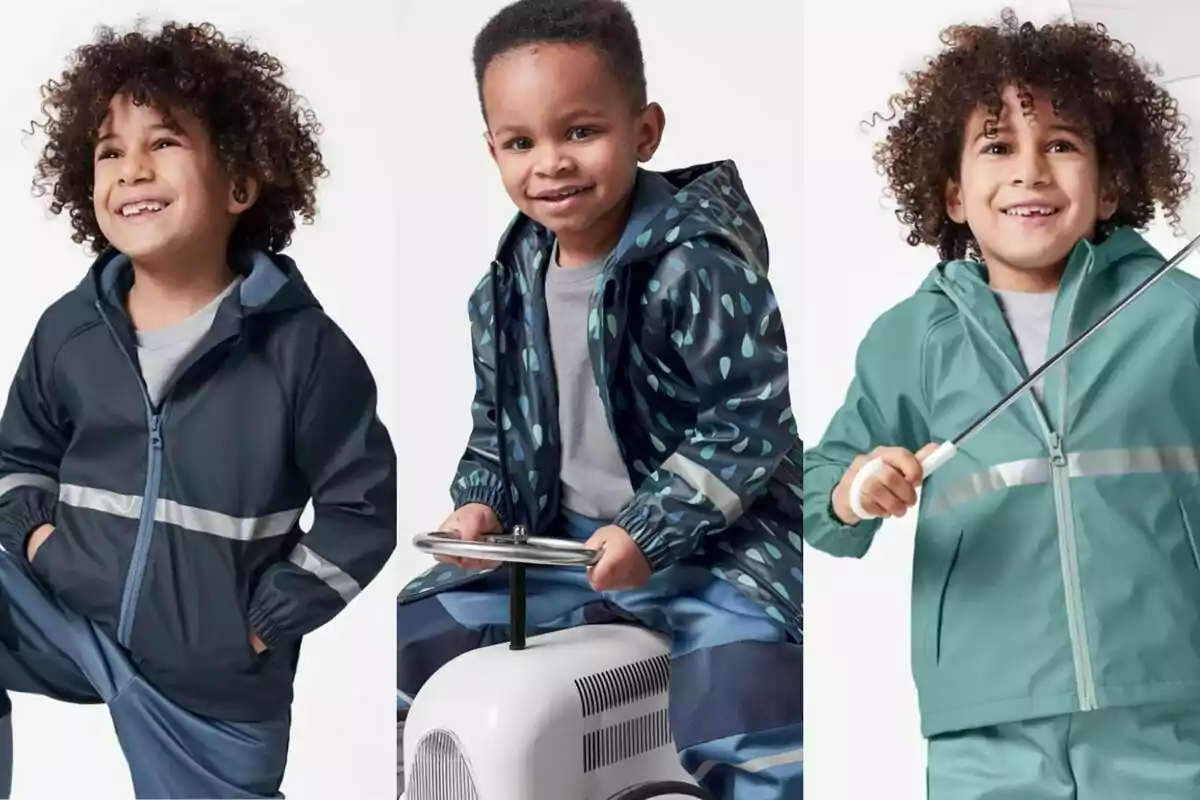 Tres nens petits somriuen portant jaquetes impermeables de diferents colors i estils, un d’ells sosté un paraigua i un altre està assegut en un cotxe de joguina.