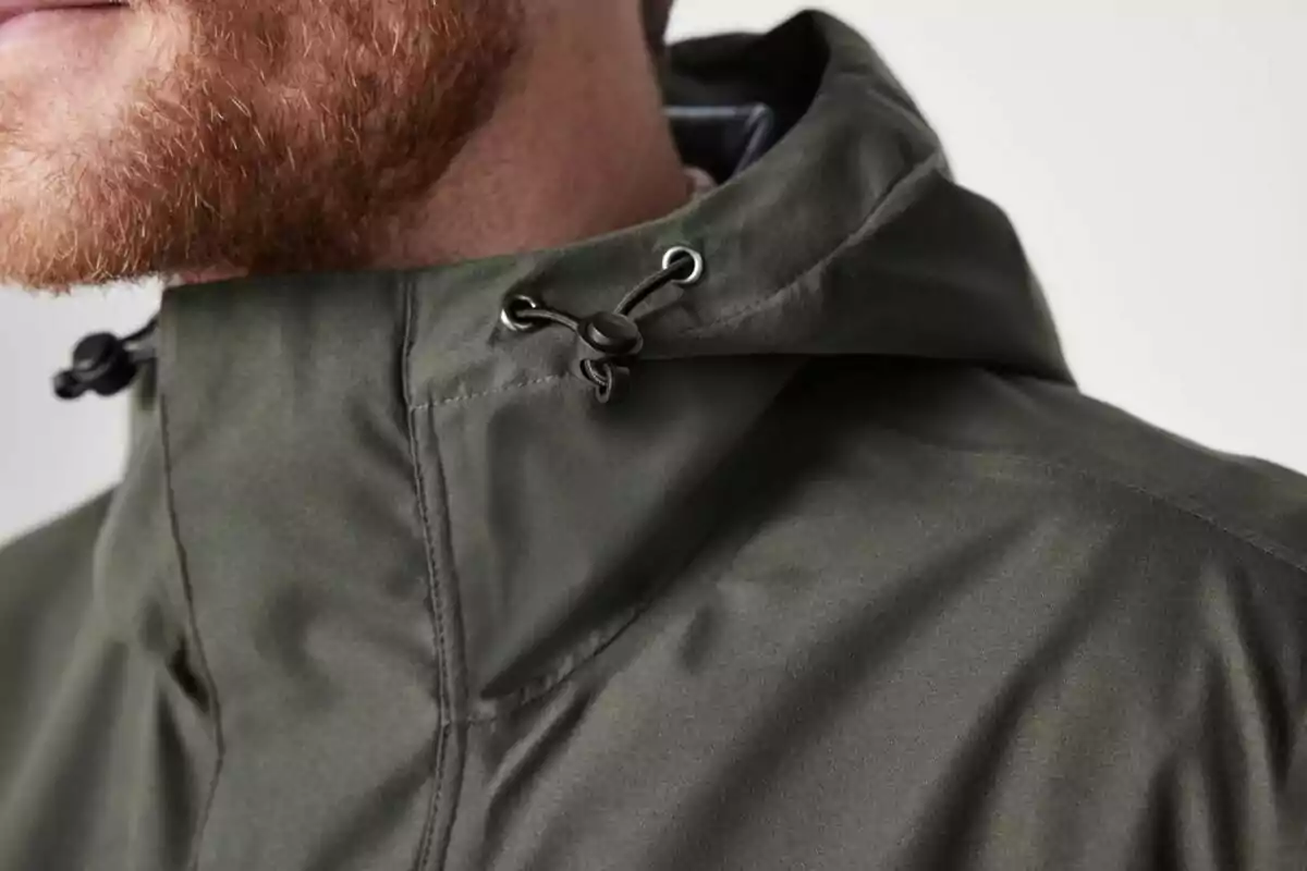 Close-up of a person with a red beard wearing a green jacket with an adjustable hood