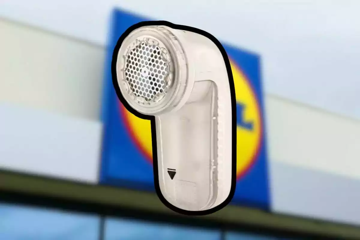 Dispositivo quitapelusas de color blanco con fondo de un letrero de supermercado desenfocado