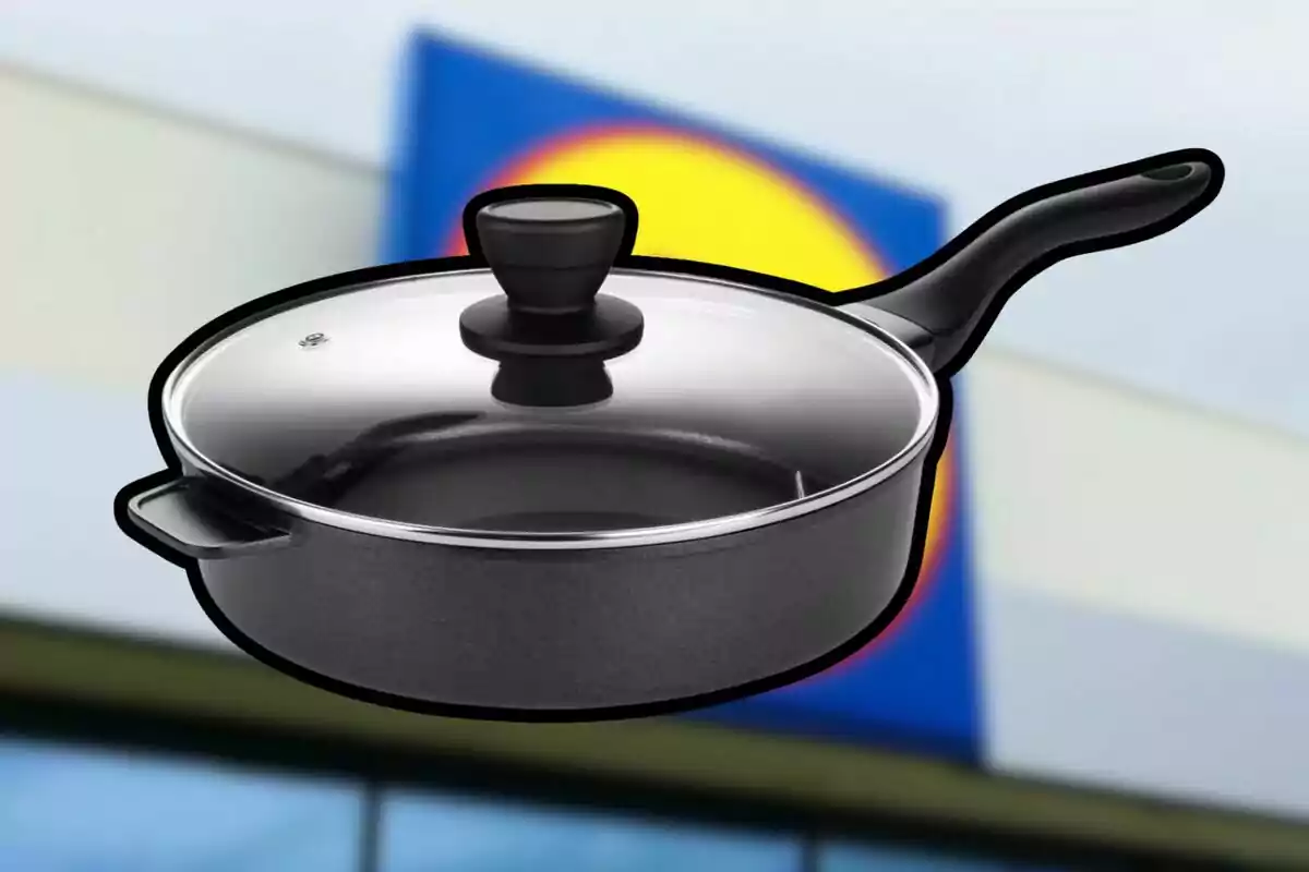 Sartén negra con tapa de cristal y mango largo frente a un fondo borroso con colores azul y amarillo Sartén negra con tapa de cristal y mango largo frente a un fondo borroso con colores azul y amarillo