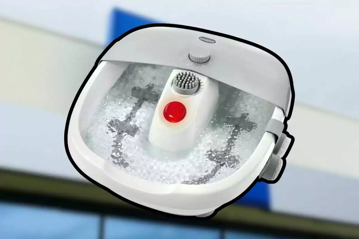 Banyera d’hidromassatge per a peus de color blanc amb aigua bombollejant i un corró de massatge al centre
