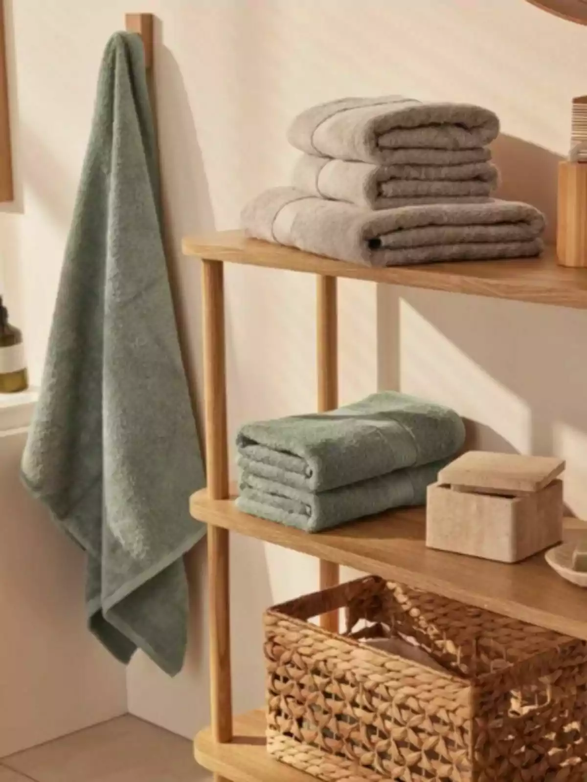 Folded and hanging towels in a bathroom with a wooden shelf and a woven basket Folded and hanging towels in a bathroom with a wooden shelf and a woven basket