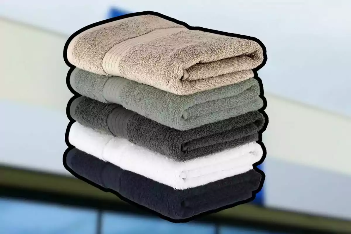 Five folded towels in different colors stacked on top of each other Five folded towels in different colors stacked on top of each other