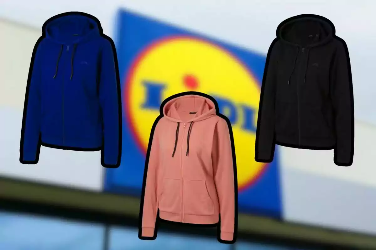 Tres sudaderas con capucha en colores azul, rosa y negro frente a un cartel borroso de la tienda Lidl