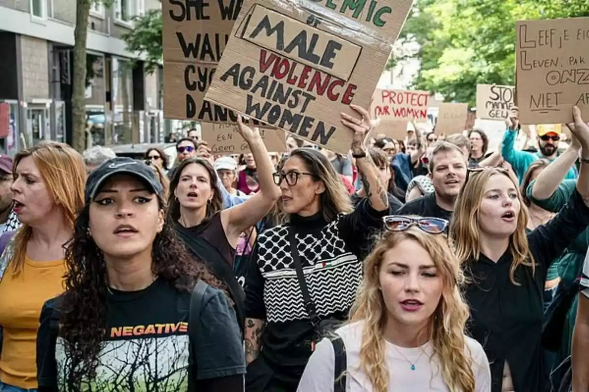 Grup de persones marxant pel carrer amb pancartes que protesten contra la violència envers les dones Grup de persones marxant pel carrer amb pancartes que protesten contra la violència envers les dones