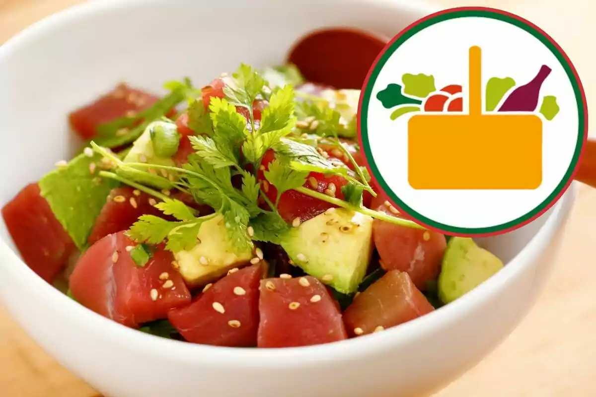 Ensalada de atún fresco con aguacate, semillas de sésamo y hojas verdes en un tazón blanco, acompañada de un gráfico de canasta de alimentos