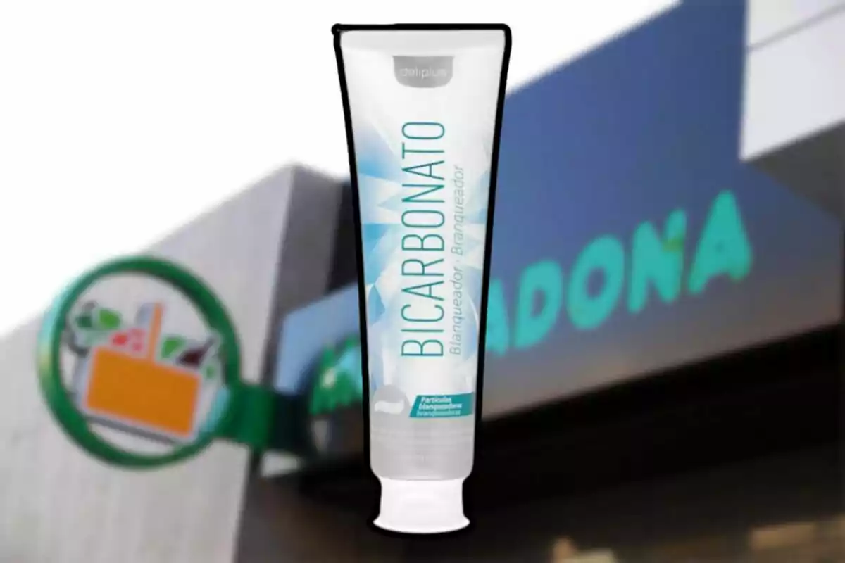 Un tubo de pasta dental de bicarbonato de la marca Deliplus frente a una tienda Mercadona desenfocada.