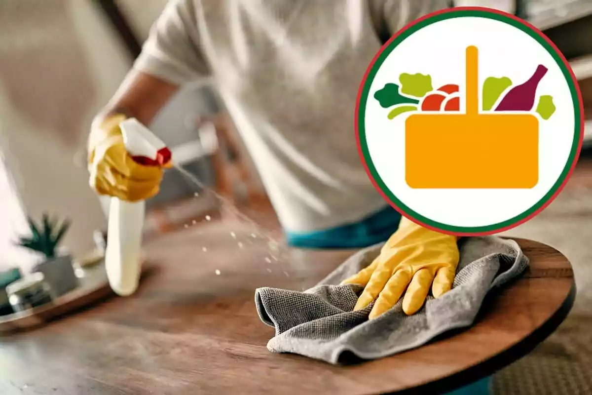 Persona limpiando una mesa de madera con guantes amarillos y un trapo mientras rocía líquido, con un ícono de canasta de compras con alimentos superpuesto. Persona limpiando una mesa de madera con guantes amarillos y un trapo mientras rocía líquido, con un ícono de canasta de compras con alimentos superpuesto.