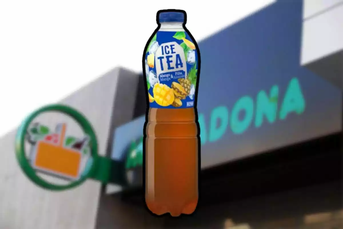 Ampolla de te gelat de mango i pinya davant d’una botiga de supermercat desenfocada