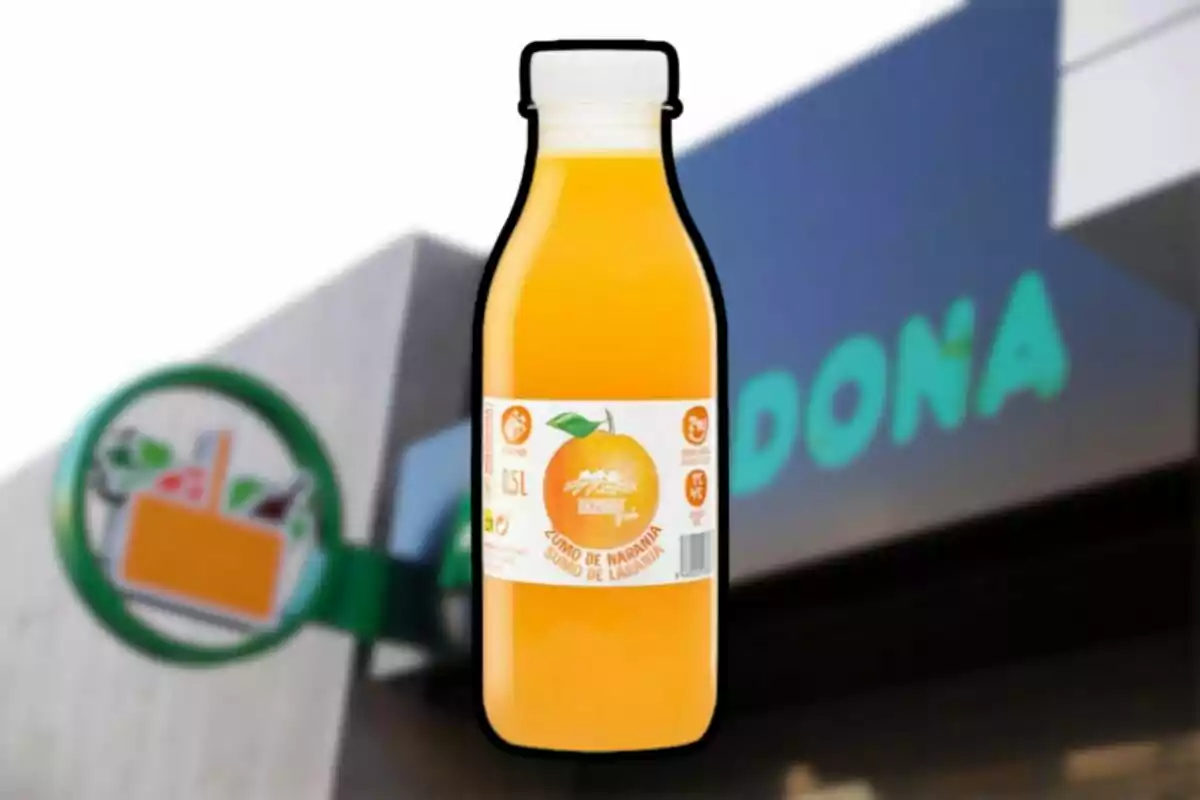 Botella de zumo de naranja frente a una tienda de Mercadona desenfocada Botella de zumo de naranja frente a una tienda de Mercadona desenfocada