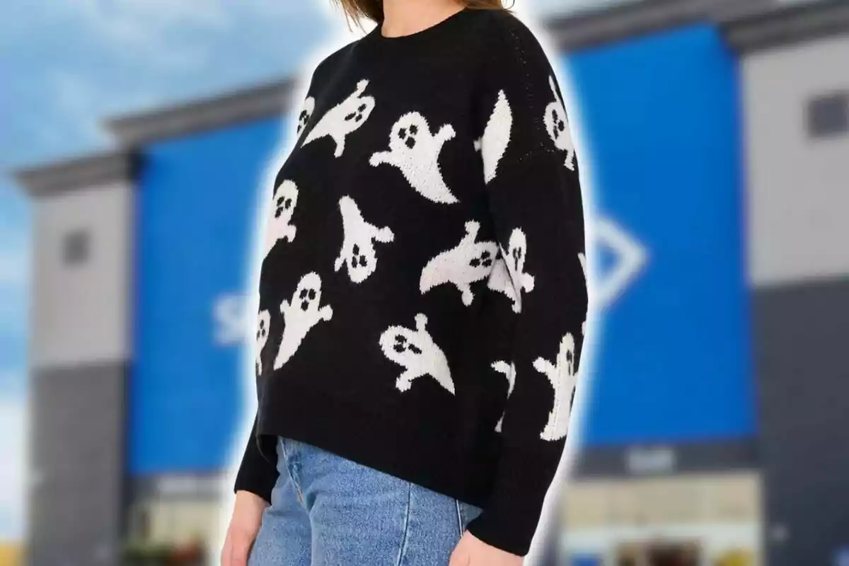Person wearing a black sweater with white ghost designs from Sam's Club and jeans in front of a building with a blurred blue facade. Person wearing a black sweater with white ghost designs from Sam's Club and jeans in front of a building with a blurred blue facade.