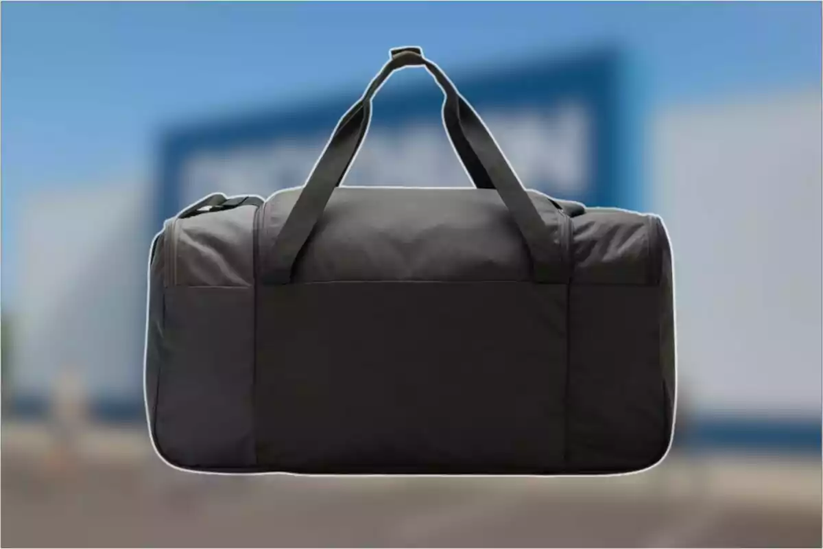 Bolsa deportiva negra con asas sobre un fondo desenfocado azul y blanco