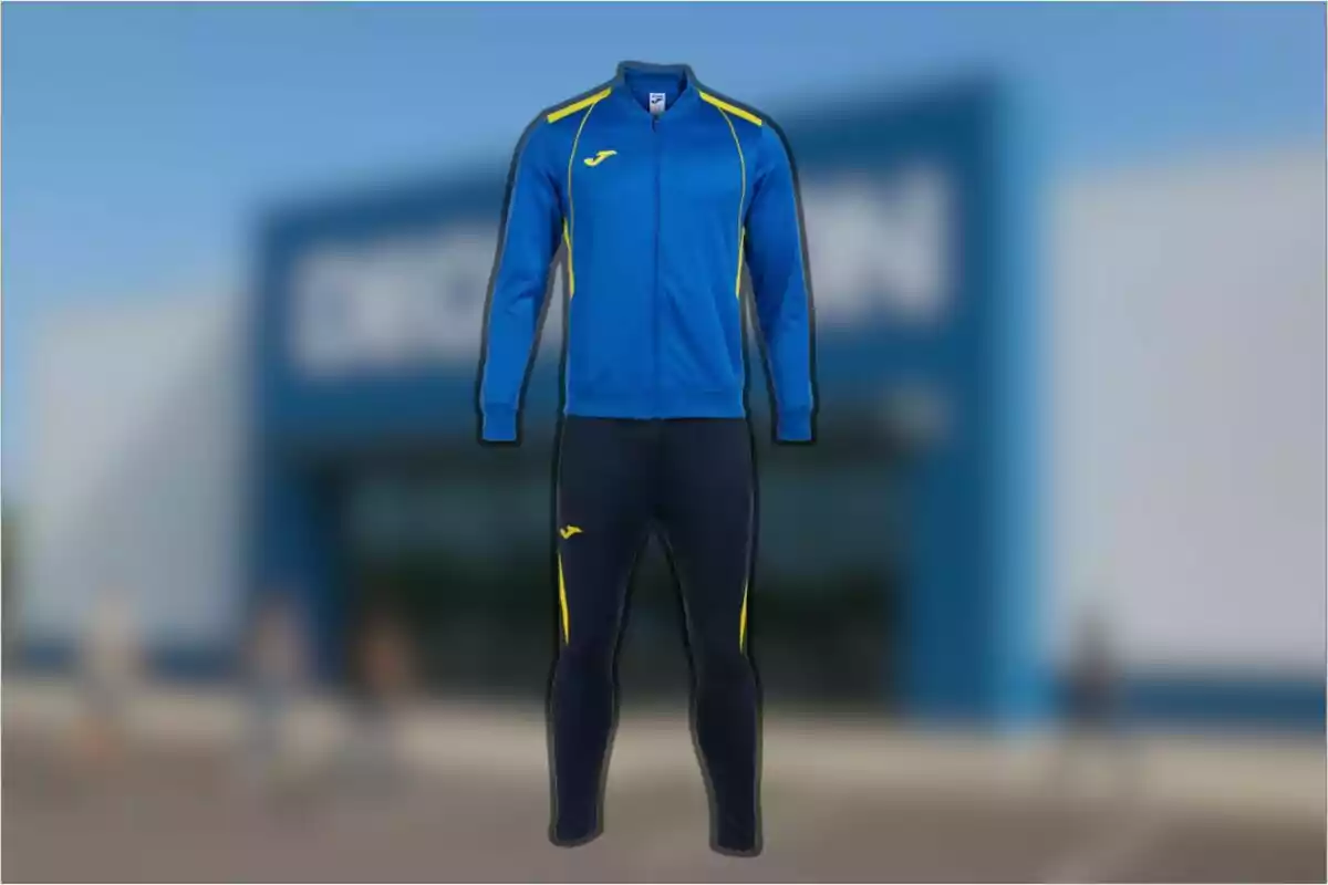 Conjunto deportivo azul con detalles amarillos compuesto por chaqueta y pantalón frente a una tienda desenfocada