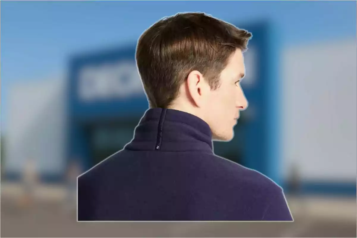 Hombre de espaldas con chaqueta azul marino y fondo desenfocado de edificio azul