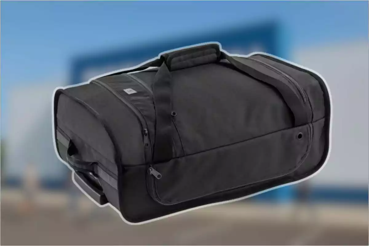 Bossa esportiva negra amb nanses i diversos compartiments sobre un fons desenfocat blau i gris