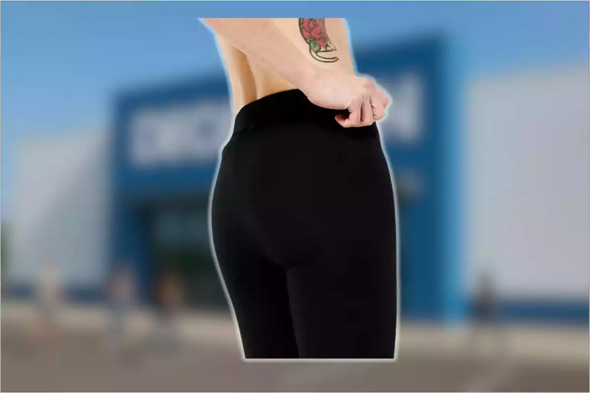 Persona de espaldas usando leggings negros con un tatuaje visible en el costado, fondo desenfocado de una tienda.