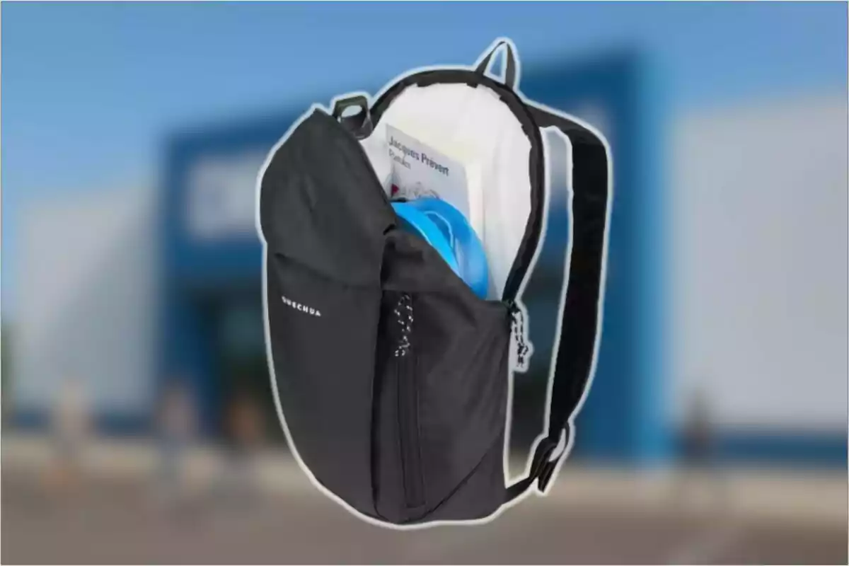 Motxilla negra oberta amb un llibre i un objecte blau a l’interior sobre un fons desenfocat d’una botiga