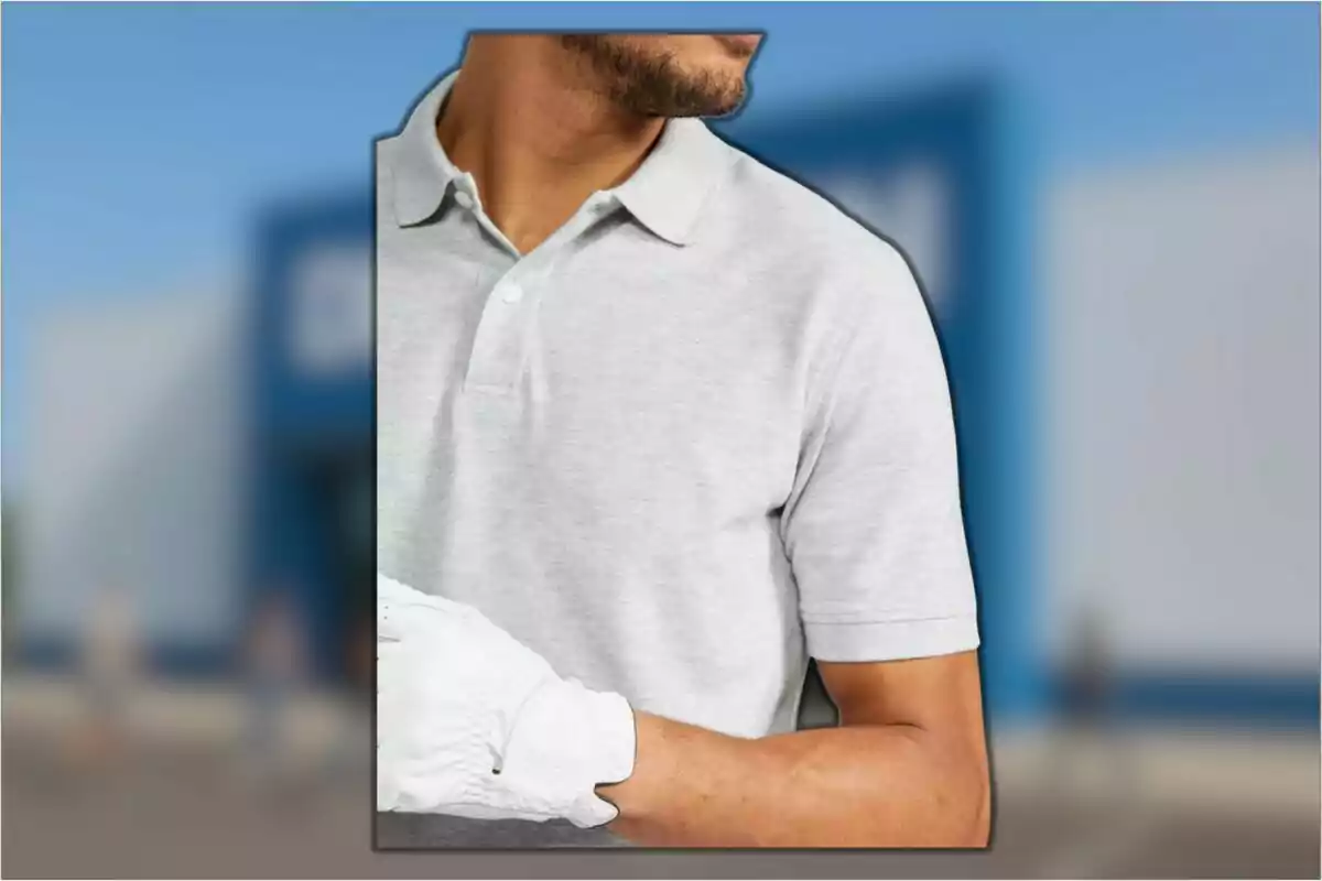 Hombre con barba usando una camiseta tipo polo gris claro y guante blanco frente a un fondo desenfocado azul Hombre con barba usando una camiseta tipo polo gris claro y guante blanco frente a un fondo desenfocado azul