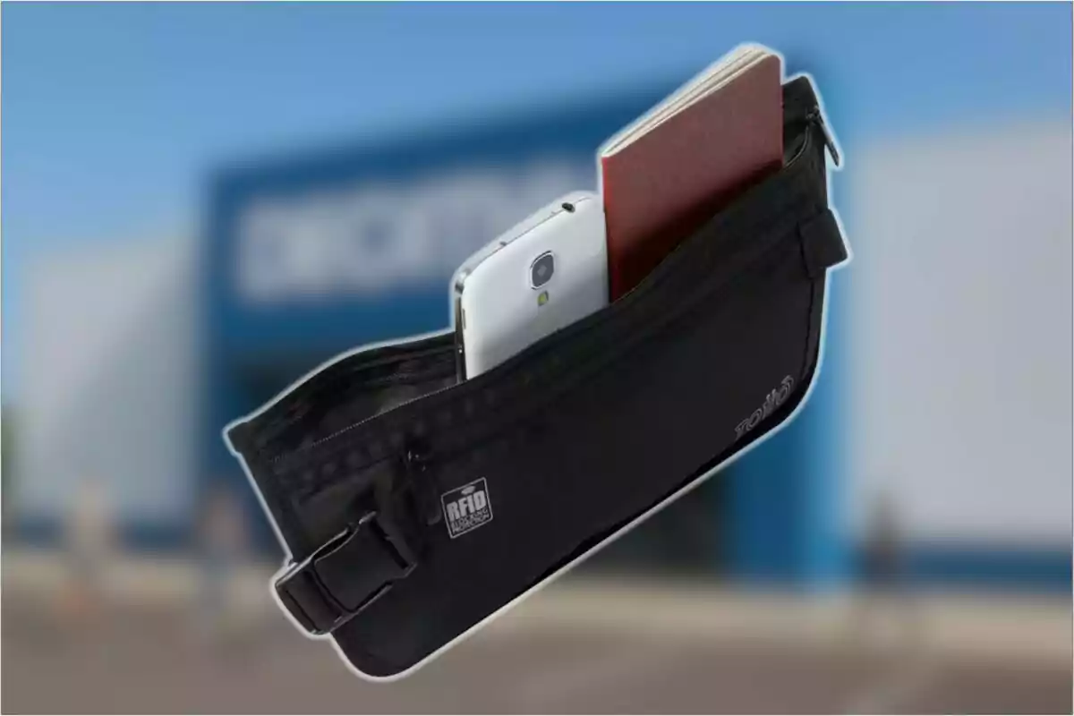 Cangurera negra con un teléfono móvil y un pasaporte en su interior sobre un fondo desenfocado