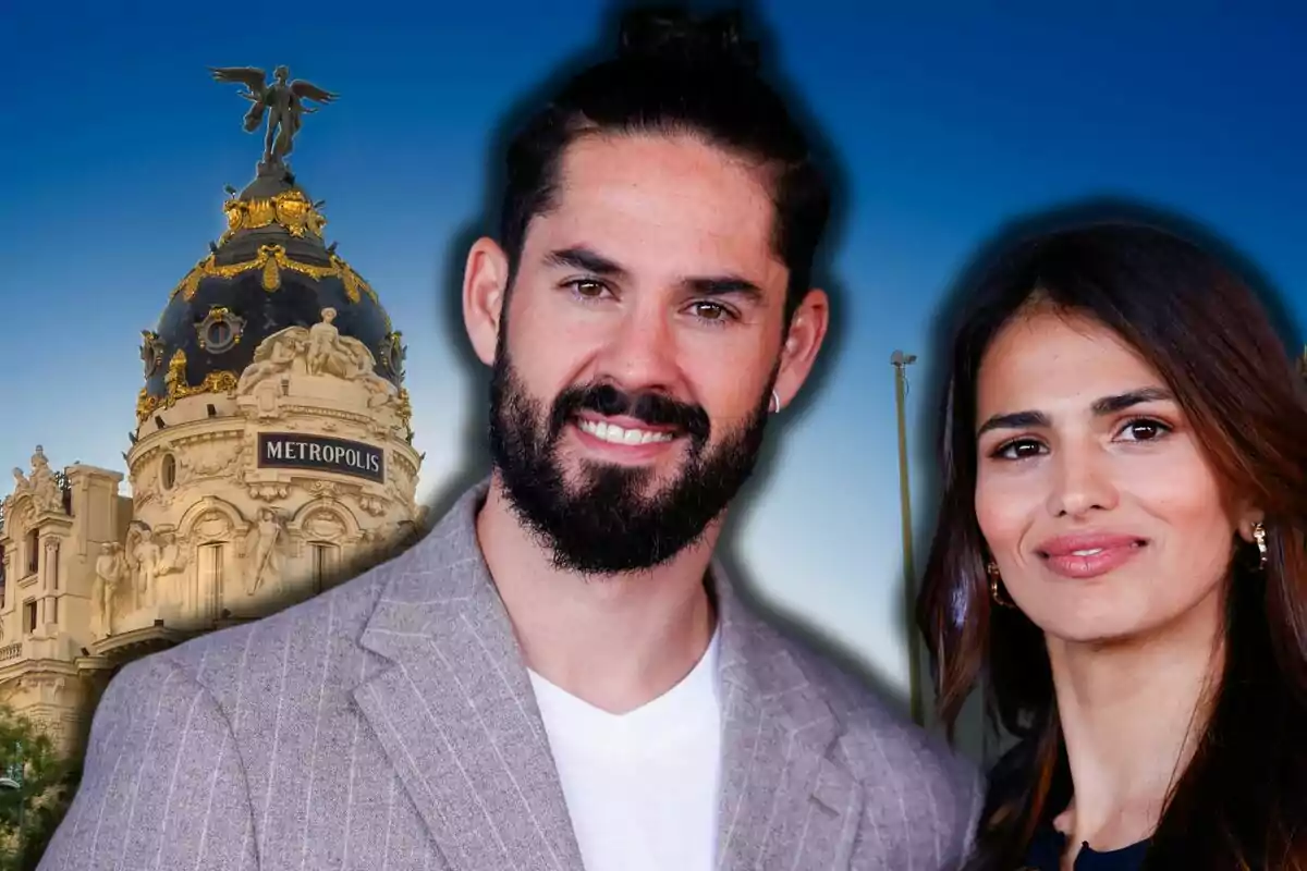 Isco Alarcón i Sara Sálamo posen somrients davant de l’edifici Metrópolis a Madrid sota un cel blau.