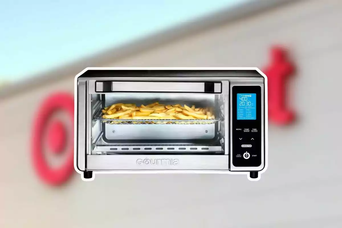 Freidora de aire plateada con papas fritas en su interior y pantalla digital encendida sobre un fondo desenfocado de una tienda Freidora de aire plateada con papas fritas en su interior y pantalla digital encendida sobre un fondo desenfocado de una tienda