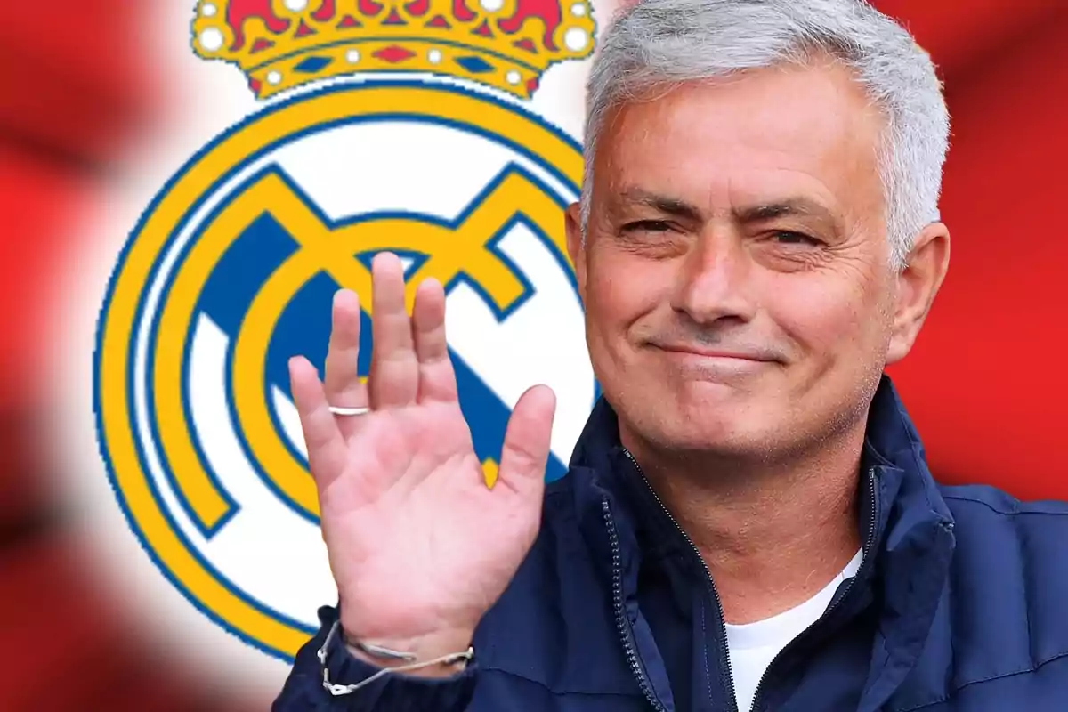 Home de cabells canosos saludant amb la mà davant de l’escut del Reial Madrid