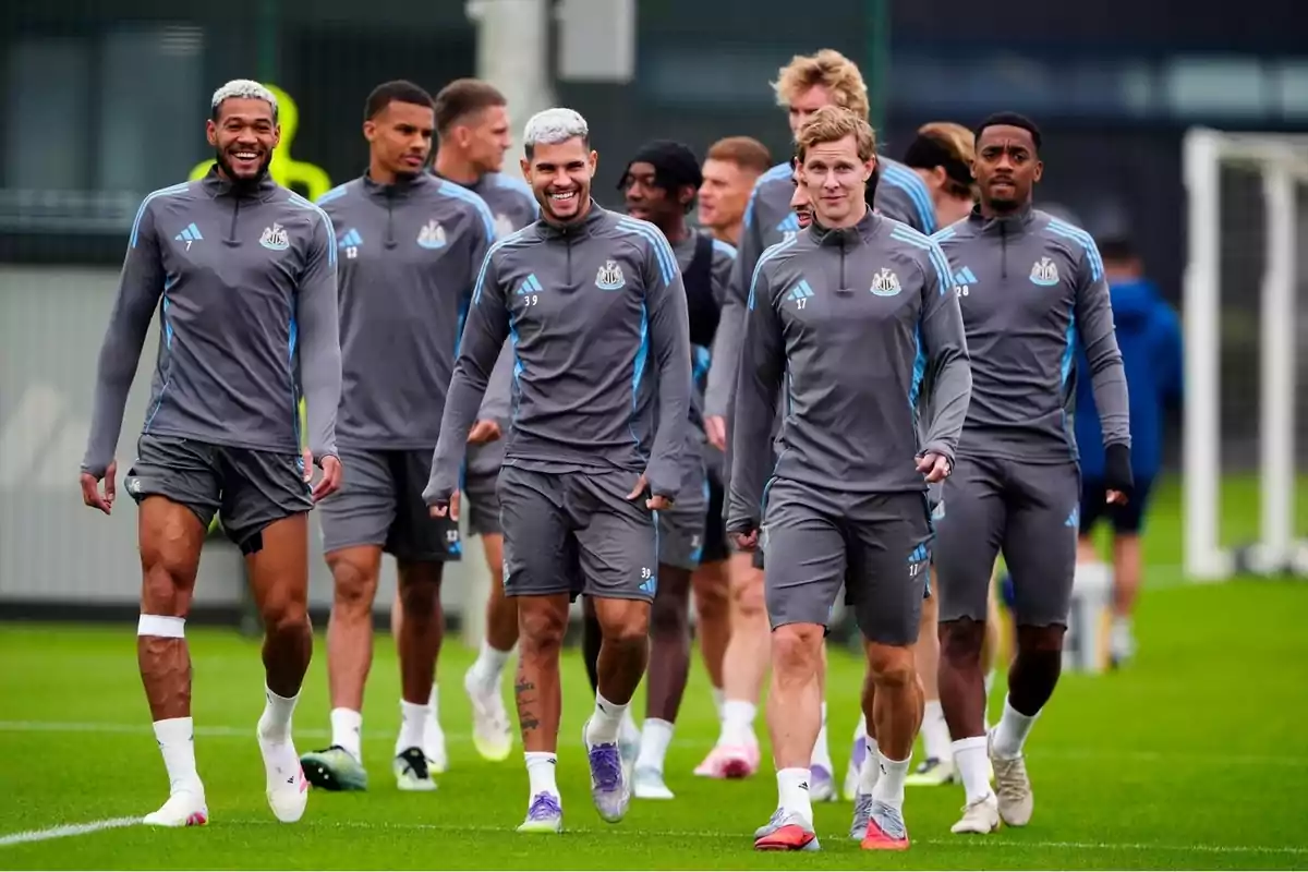 Grup de futbolistes amb uniforme gris entrenant i caminant junts en un camp de gespa Grup de futbolistes amb uniforme gris entrenant i caminant junts en un camp de gespa