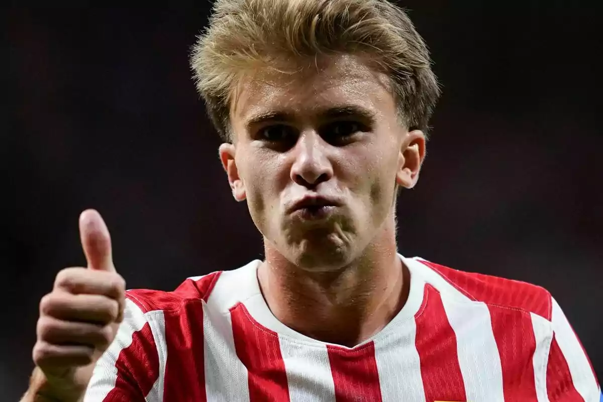 Jove amb samarreta de ratlles vermelles i blanques fent un gest de petó i aixecant el polze en senyal d’aprovació Jove amb samarreta de ratlles vermelles i blanques fent un gest de petó i aixecant el polze en senyal d’aprovació