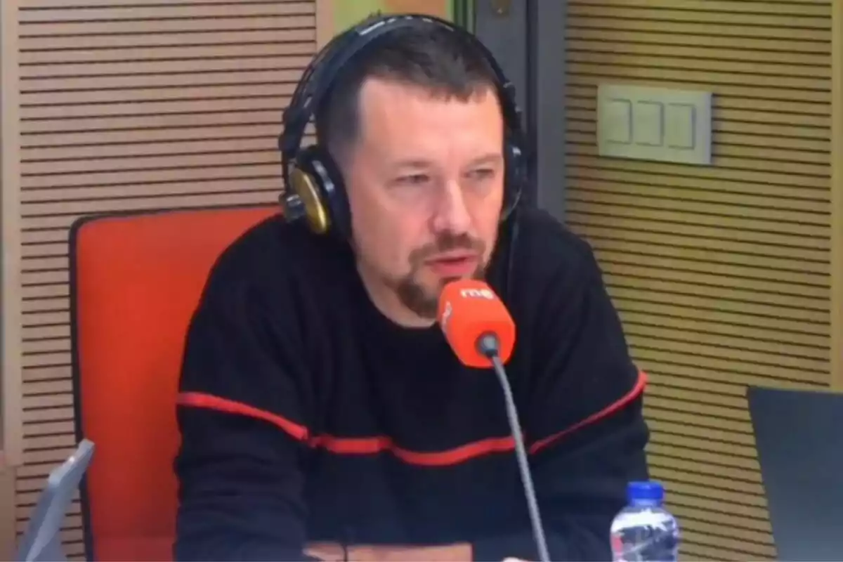 Home amb auriculars i micròfon vermell parlant en una cabina de ràdio