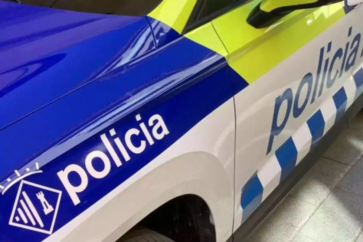 Cotxe patrulla de la policia amb colors blau, blanc i groc i logotip a la porta