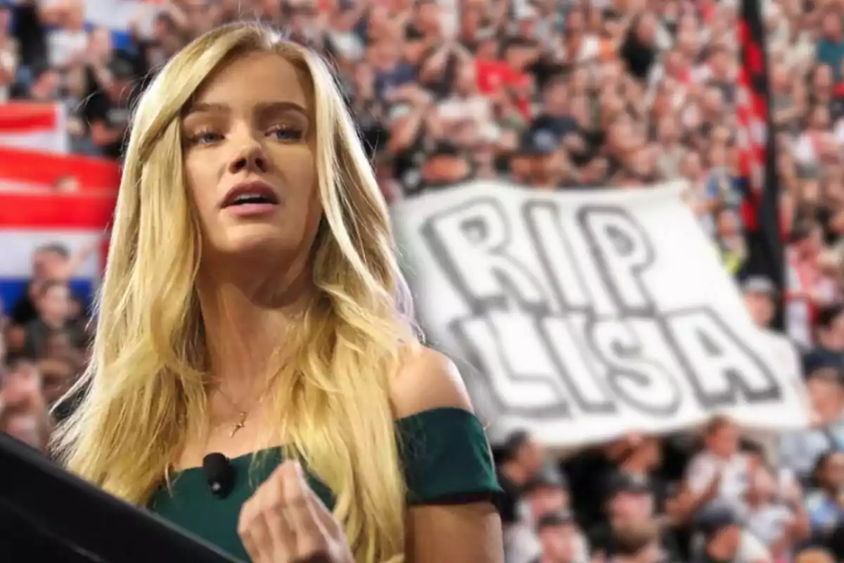 Dona rossa de cabell llarg amb vestit verd fosc parlant davant d’un micròfon amb una multitud al fons i un cartell que diu RIP LISA