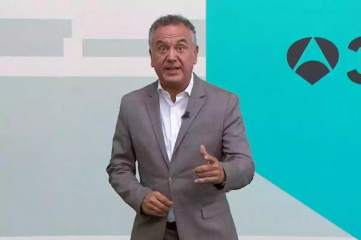 Roberto Brasero amb els cabells curts i canosos, amb vestit gris i camisa blanca, parlant davant d’una pantalla blava amb un logotip geomètric negre. Roberto Brasero amb els cabells curts i canosos, amb vestit gris i camisa blanca, parlant davant d’una pantalla blava amb un logotip geomètric negre.