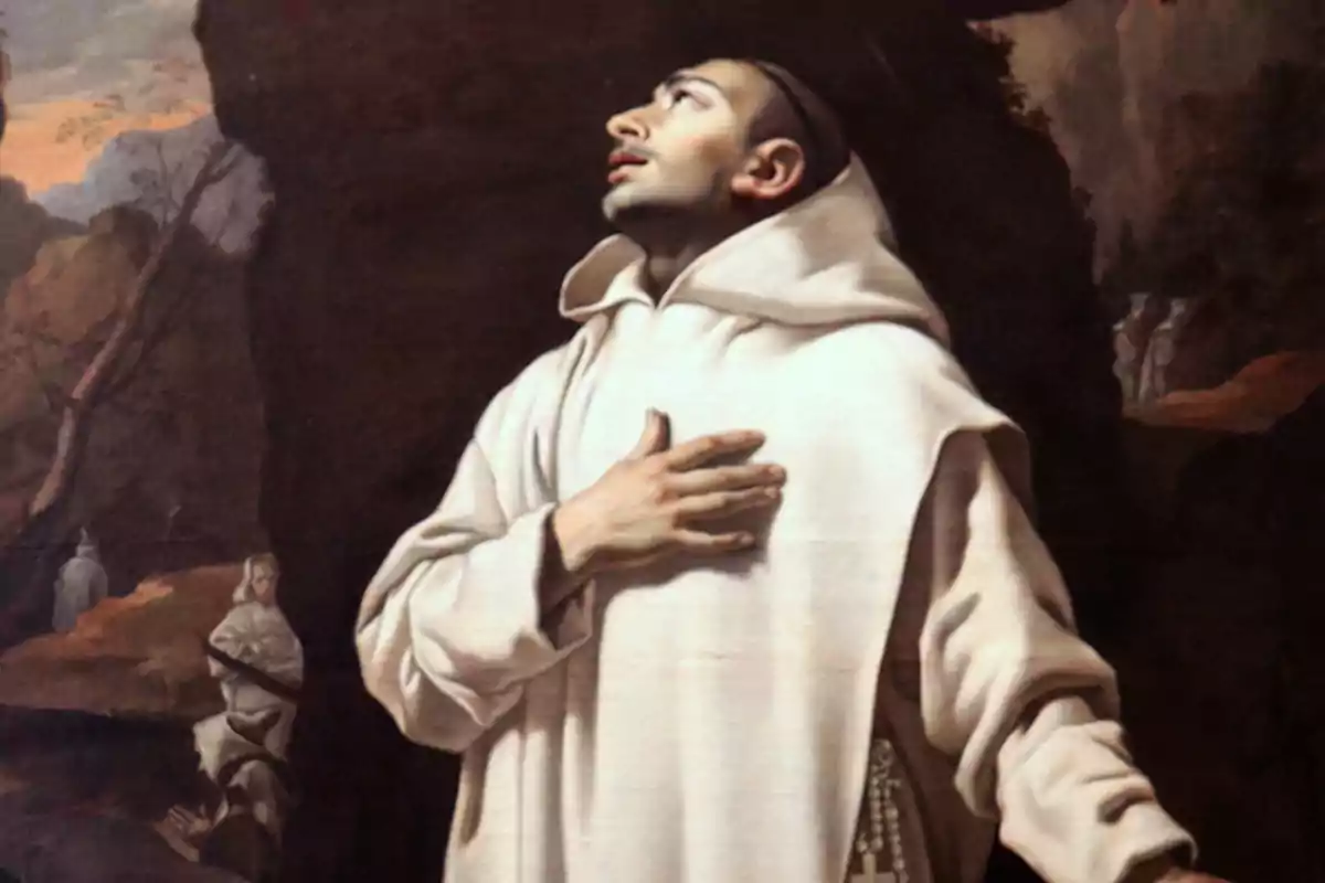 Un monje con hábito blanco mira hacia arriba con expresión de devoción y una mano en el pecho mientras al fondo se observan otros monjes en un paisaje natural.