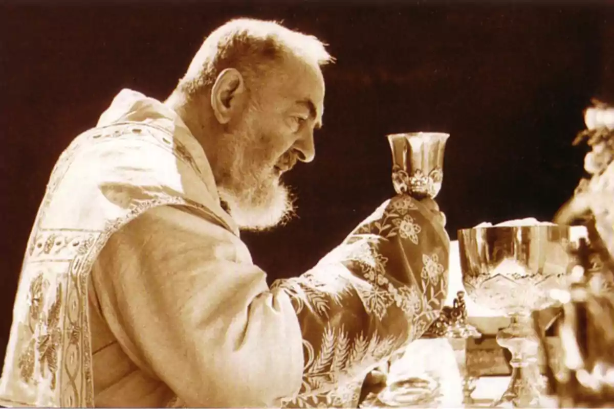 Sacerdote de barba blanca celebrando una misa y levantando un cáliz decorado Sacerdote de barba blanca celebrando una misa y levantando un cáliz decorado