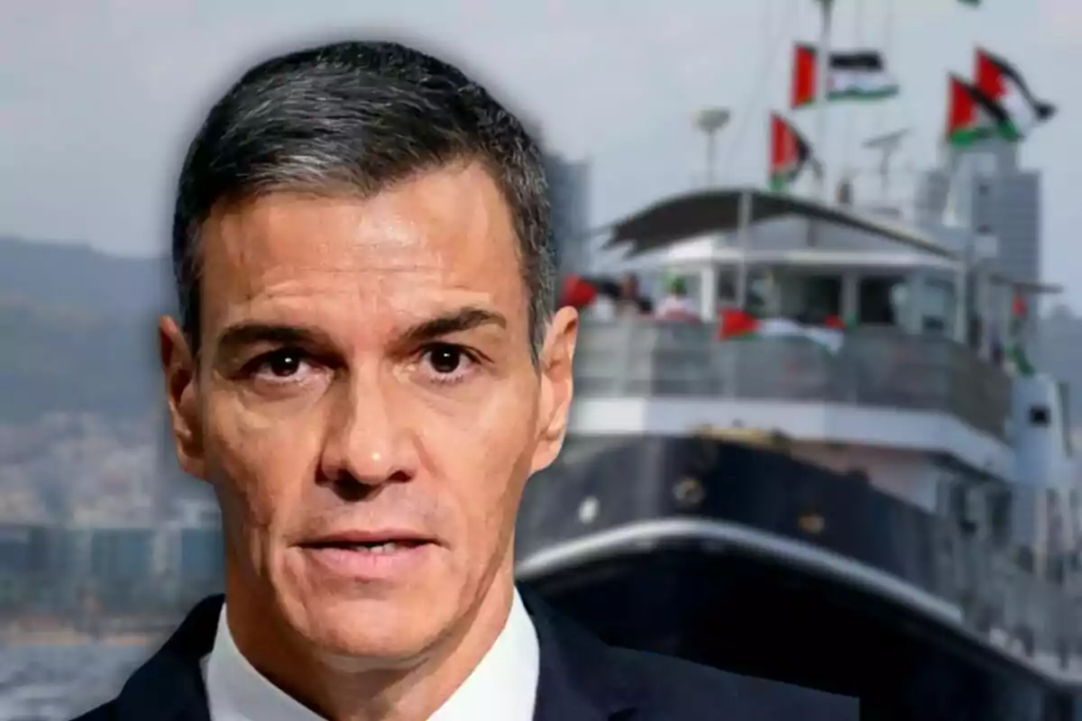 Home de cabells curts i canosos en primer pla amb un vaixell decorat amb banderes al fons