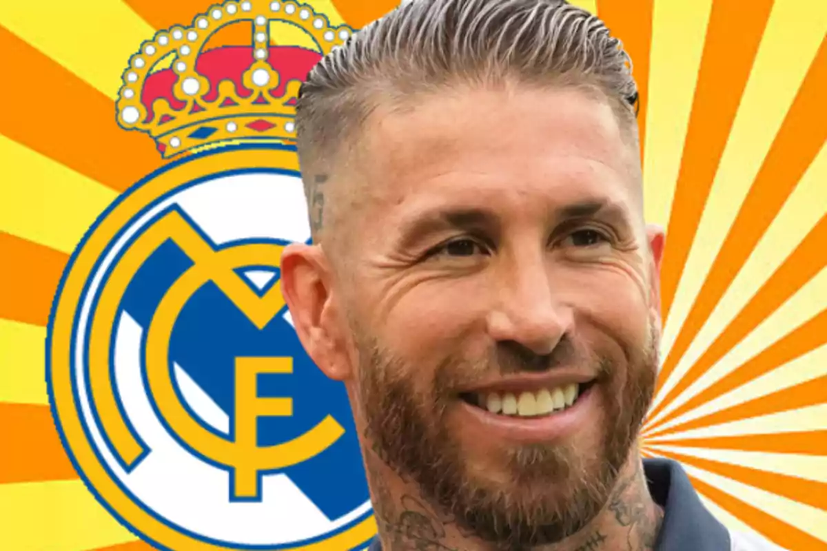 Smiling man with a beard and short slicked-back hair in front of the Real Madrid crest with a yellow and orange background in rays.