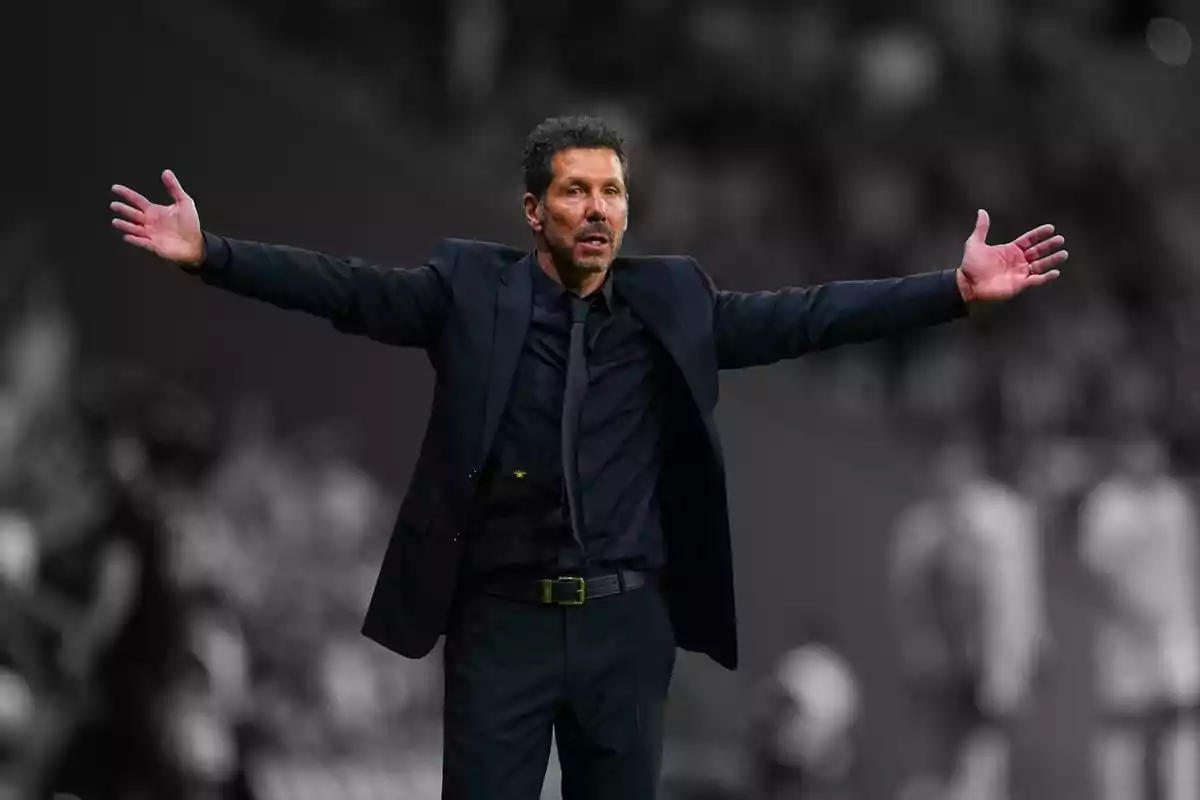 Entrenador de futbol vestit amb un vestit negre amb els braços estesos en un estadi Entrenador de futbol vestit amb un vestit negre amb els braços estesos en un estadi