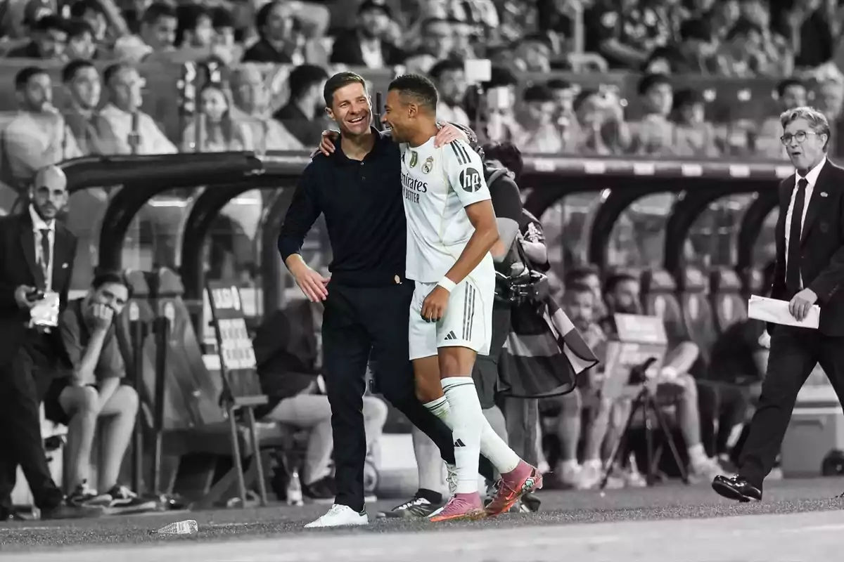 Dues persones somriuen i s’abracen al camp de futbol mentre el fons és en blanc i negre i elles en color. Dues persones somriuen i s’abracen al camp de futbol mentre el fons és en blanc i negre i elles en color.