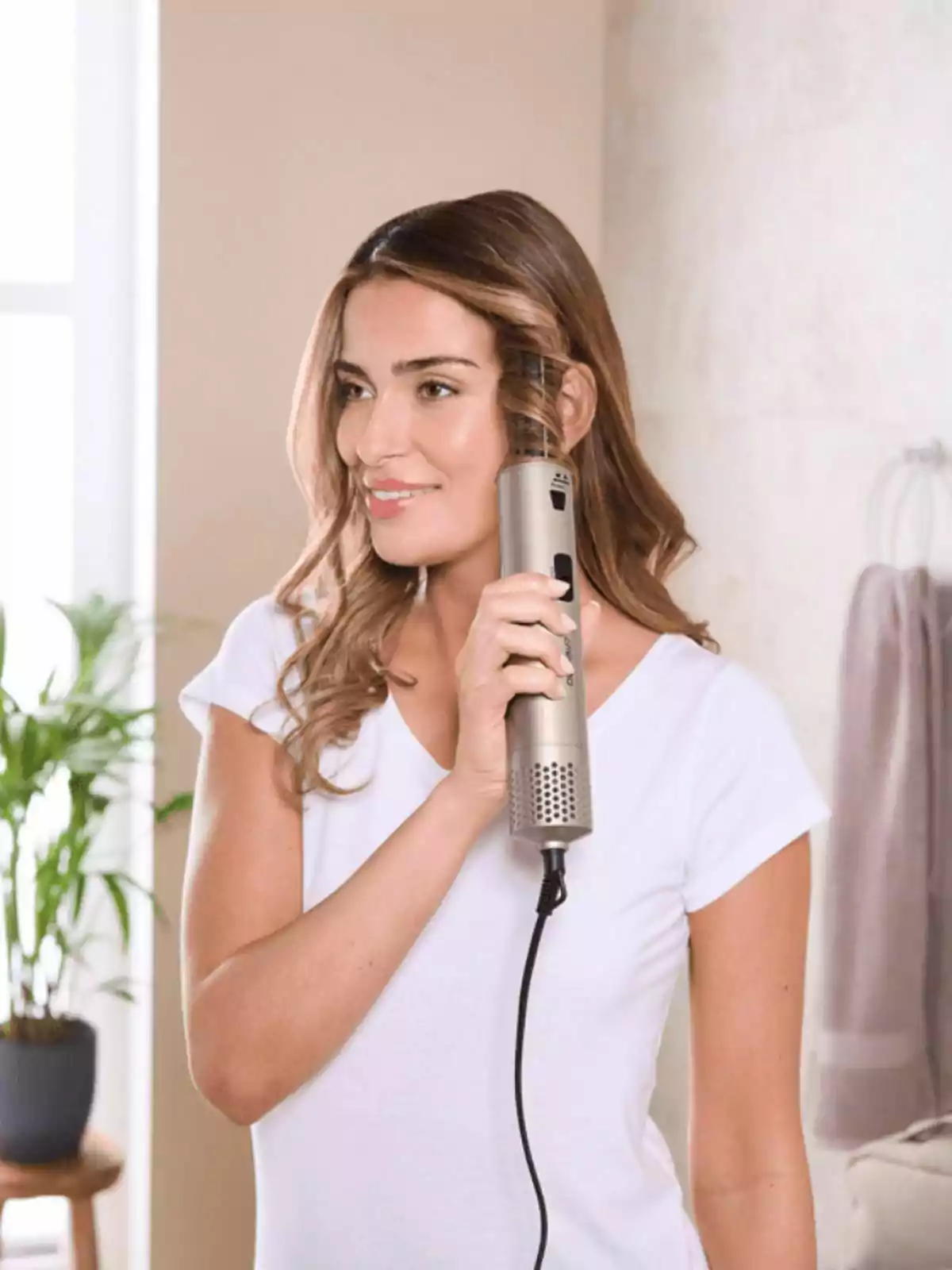 Mujer usando un rizador de cabello eléctrico en un baño moderno